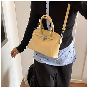Detail of pale yellow square crossbody bag featuring a classic metal padlock and top handle