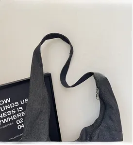 Dettaglio della borsa tote in denim grigio scuro con tracolla larga e cerniera in metallo