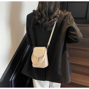 Model wearing a chic beige textured crossbody phone bag with woven design and silver clasp