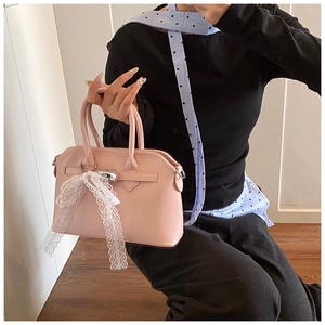 Detail of light pink faux leather handbag with silver twist lock and lace bow decoration