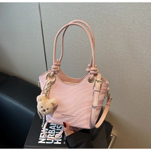 Detailed shot of pink wavy textured shoulder bag with golden rings and a cute bear charm