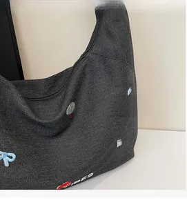 Dettaglio ravvicinato della borsa in denim nero con ricami colorati e scritta VIBES