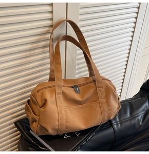 Detail view of large brown canvas travel bag with side pockets and sturdy double handles