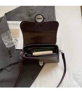 Vue intérieure montrant les compartiments spacieux du sac bandoulière en cuir brun
