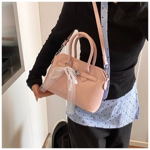 Close-up of pink crossbody bag featuring white lace bows and elegant pearl strand charms