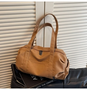 Detail of a brown canvas travel bag with sturdy handles and front pocket for fitness use
