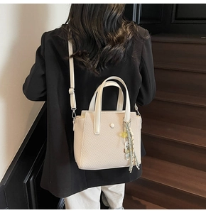 Détail du sac seau blanc cassé avec texture tissée sergée et pompon à perle jaune
