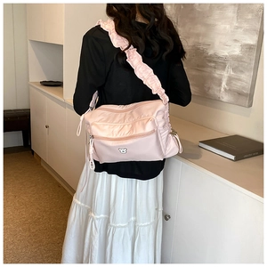 Détail du sac bandoulière en nylon rose avec bandoulière froncée et broderie d'ours