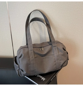 Detailed view of the dark grey canvas duffel bag featuring dual zipper and side pocket