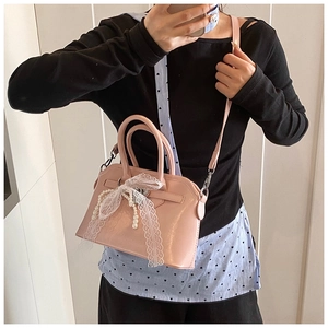 Detailed view of pink handbag featuring elegant white lace bow and pearl decoration