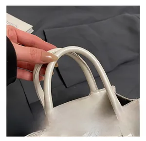 Detail of white bow bag showing the thick rounded handle and premium textured synthetic leather