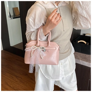 Detail of pink handbag featuring white lace bow and elegant pearl ornaments