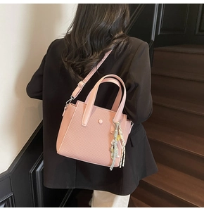 Détail du sac seau rose tressé avec bijou de sac en foulard porté par un mannequin