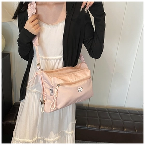 Détail du sac seau en nylon rose avec logo ours blanc et bandoulière à volants réglable