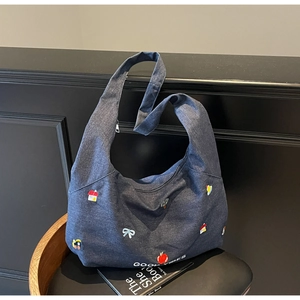 Dettaglio della borsa tote in denim blu con toppe colorate e stampa Good Vibes