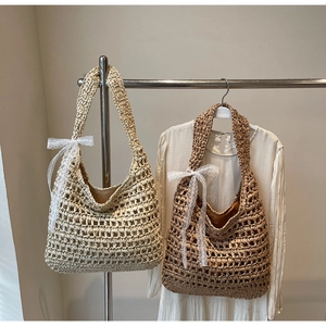 Detail of hollow-out woven straw tote bags in beige and brown with lace bow accents