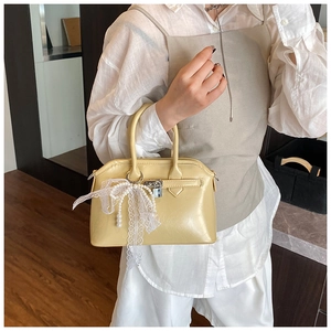 Detail of a creamy yellow Boston bag featuring lace bow and pearl chain decoration