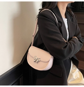 Detailed view of pink saddle bag with silver bow buckle worn on a shoulder strap