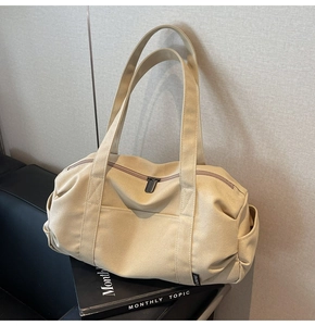 Detail of canvas travel bag featuring large front pocket and side storage compartments