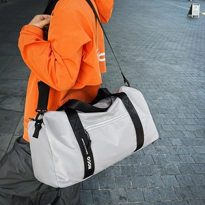 Modèle extérieur portant un sac de sport gris étanche avec sangles noires et texte