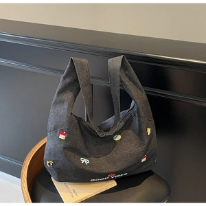 Dettaglio della borsa tote in denim nero con ricami colorati e scritta Good Vibes