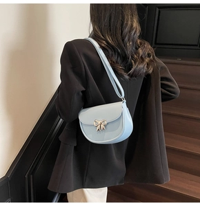 Detail of light blue semi-circle saddle bag with silver bow on a black blazer