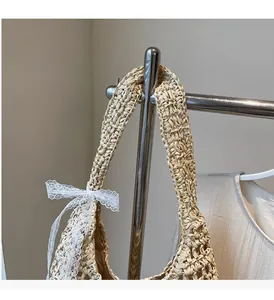 Close-up of hand-woven straw tote bag featuring decorative white lace bow detailing