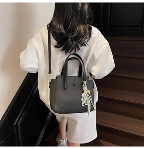 Sac seau noir texture carbone avec pendentif ours porté par un mannequin en intérieur
