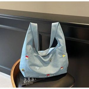 Dettaglio della borsa tote in denim azzurro con ricami colorati e scritta Good Vibes
