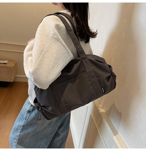 Detail view of large grey canvas travel bag with side pockets and sturdy shoulder straps