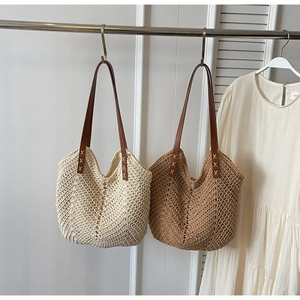 Close-up of woven tote bags with leather straps and detailed X-shaped cross stitching