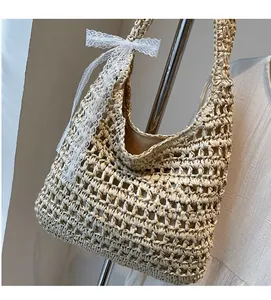 Detail of beige straw tote bag featuring intricate openwork weave and lace bow accent