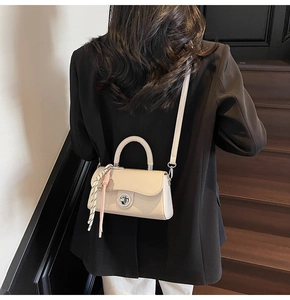 Vue détaillée d'un sac bandoulière beige avec fermoir argenté et détail de foulard