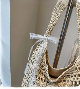 Detail of woven straw tote bag with lace bow decoration and secure zipper closure