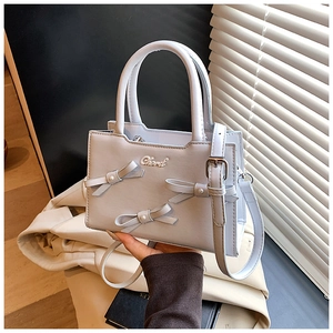 Close-up of light blue handbag with pearl-studded bows and metal Chord logo detail