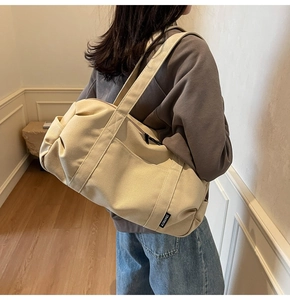 Detailed close-up of the beige canvas travel bag featuring reinforced straps and side pocket