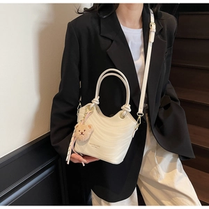 White wave texture bucket bag with detachable strap and cute bear charm shown on a model