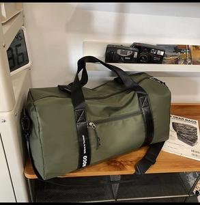 Sac de voyage vert foncé imperméable avec sangle motivante posé sur un bureau