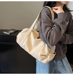 Detail view of large beige canvas travel bag with wide handles and side pocket