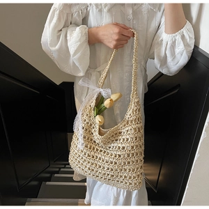 Detail of hand-crocheted straw tote bag with large hollow weave and lace bow accent