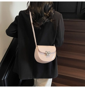 Rear view of a model wearing a soft pink leather saddle bag with silver bow detail