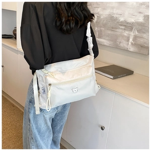 Détail du sac seau en nylon blanc avec bandoulière à volants et poches zippées devant