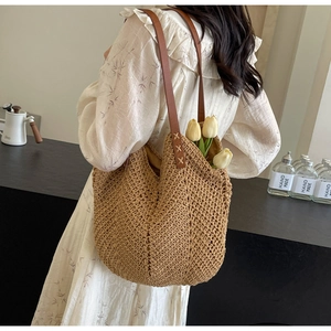 Detail of herringbone weave texture and brown leather strap on oversized summer tote bag