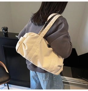 Close-up of cream canvas travel bag with reinforced straps and spacious cylinder design