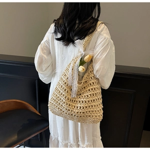 Détail d'un sac à bandoulière en paille tressée beige avec un élégant nœud en dentelle blanche