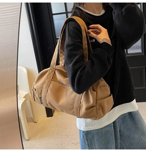 Model wearing a khaki canvas duffel bag showing high capacity for travel and gym use