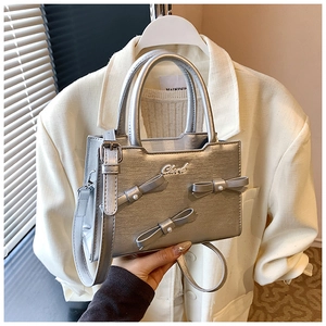 Detail showing the silver handbag with pearl bow accents and fine metallic texture