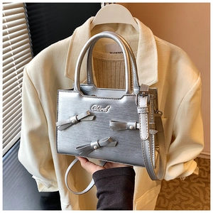 Detail of silver bow handbags with pearl accents on a metallic fashion crossbody bag