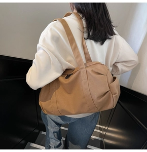 Large khaki canvas travel bag shown on shoulder, featuring durable fabric and side pocket