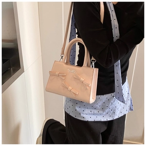 Close-up of pink bow decoration and Garel metallic logo on the stylish handbag